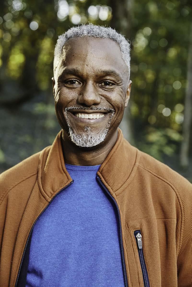 James E. Page Jr., smiling outdoors in a brown jacket over a blue shirt.